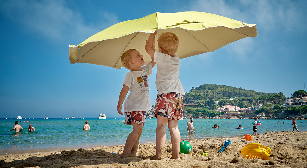 ビーチで日傘を設置する子供の兄弟